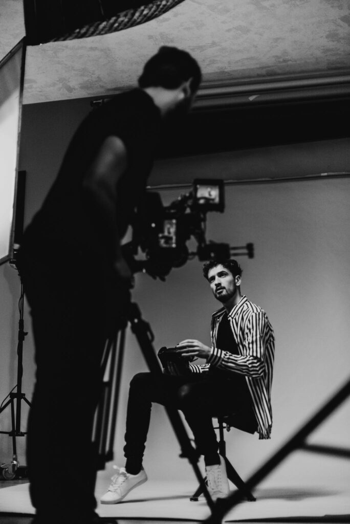 Artistic black and white fashion shoot featuring a male model in a studio setting.